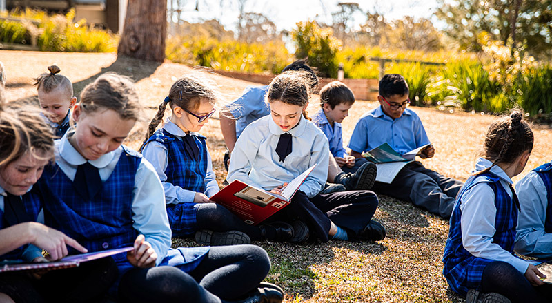 Students reading outdoors at St Thomas Aquinas Catholic Primary Springwood