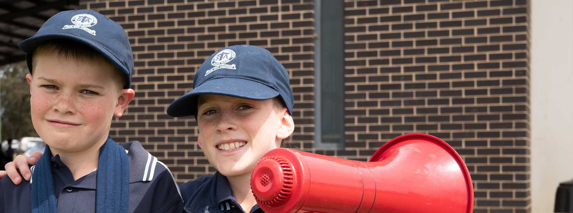Two St Thomas Aquinas Springwood students. One has a broken arm and the other has a megaphone.